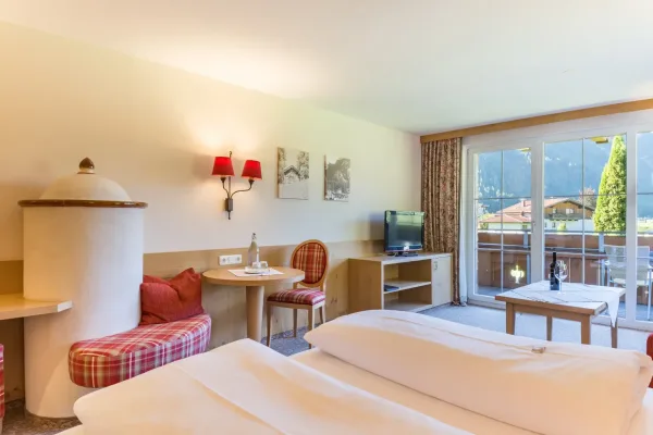 Junior Suite - Blick vom Bett auf Kachelofen und Balkon